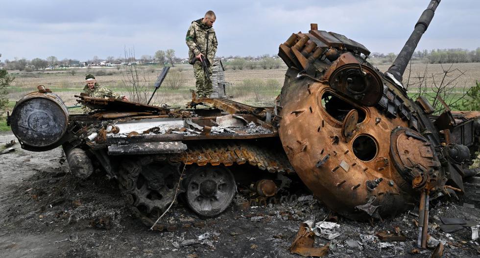 Militares ucranianos miran un tanque ruso destruido en una carretera en la aldea de Rusaniv, en la región de Kiev, el 16 de abril de 2022. (Genya SAVILOV / AFP).