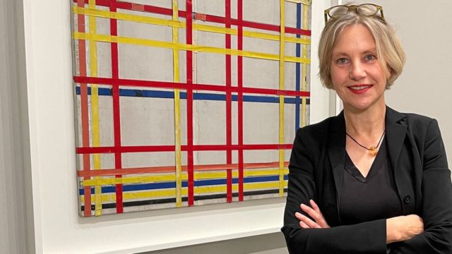 Curator Susanne Mayer Bowser poses in front of a Piet Mondrian painting "New York City I" In the Museum of the Art Collection of North Rhine-Westphalia.