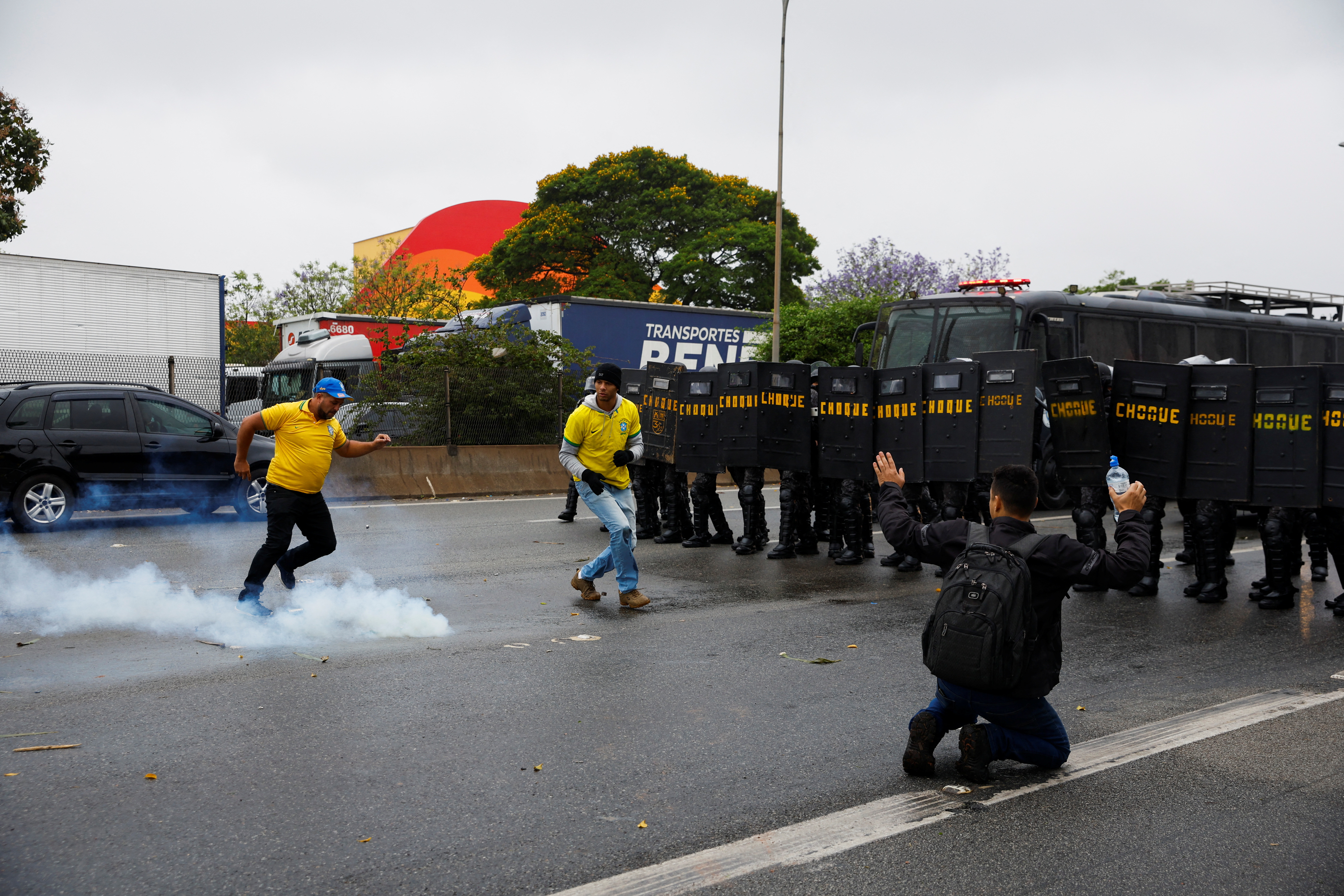 Riot police stand by as supporters of Brazilian President Jair Bolsonaro's attempts to kick a gas canister